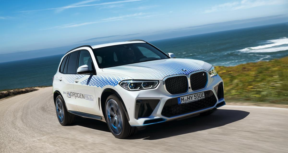 BMW iX5 hydrogène - Voiture à hydrogène blanche sur une route avec la mer en fond