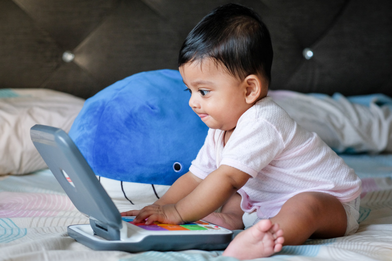 *electromenager bébé*  un bébé tape sur un petit ordinateur pour enfant avec un air concentré